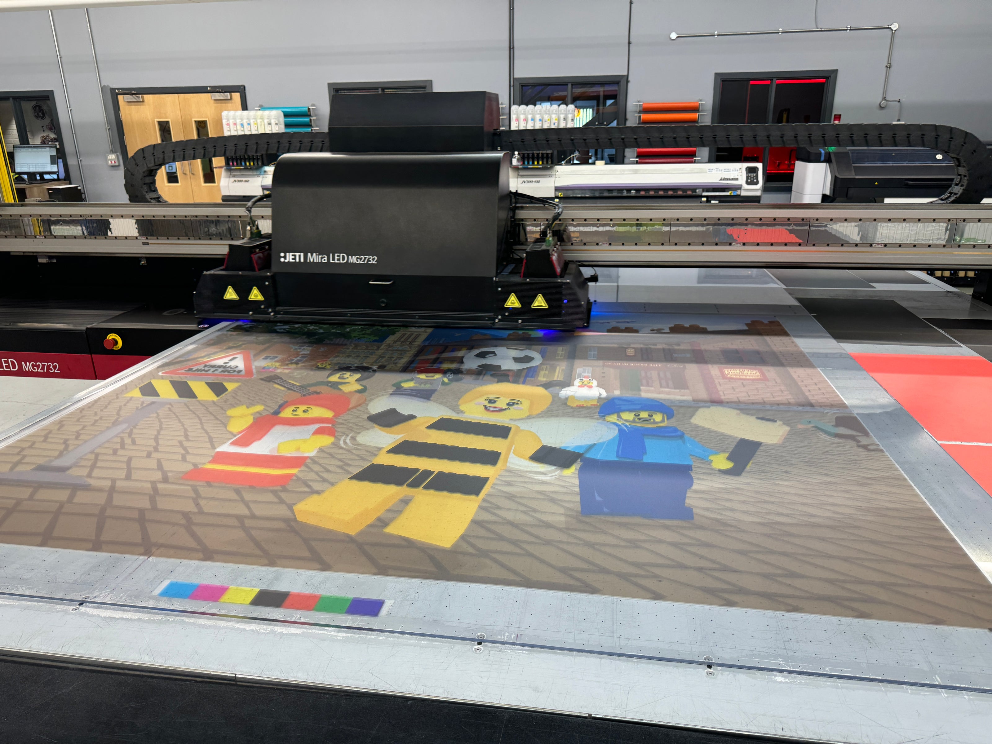 A large printer printing a Lego sign at Visual Group's manufacturing facility